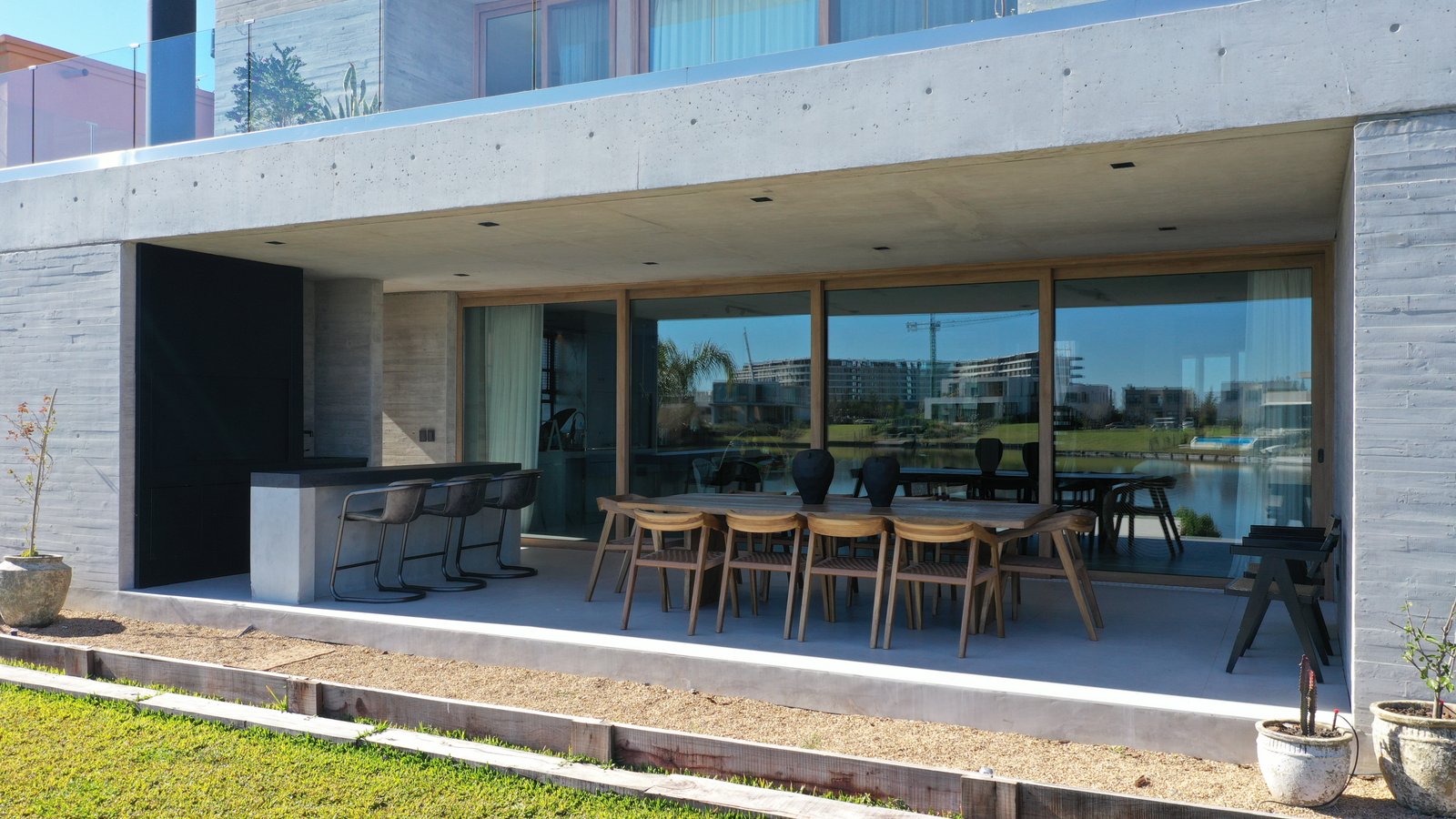 Fachada moderna de hormigón visto con deck de madera y pérgola — proyecto CASA MHN, por Hermann Arquitectos, en Nordelta